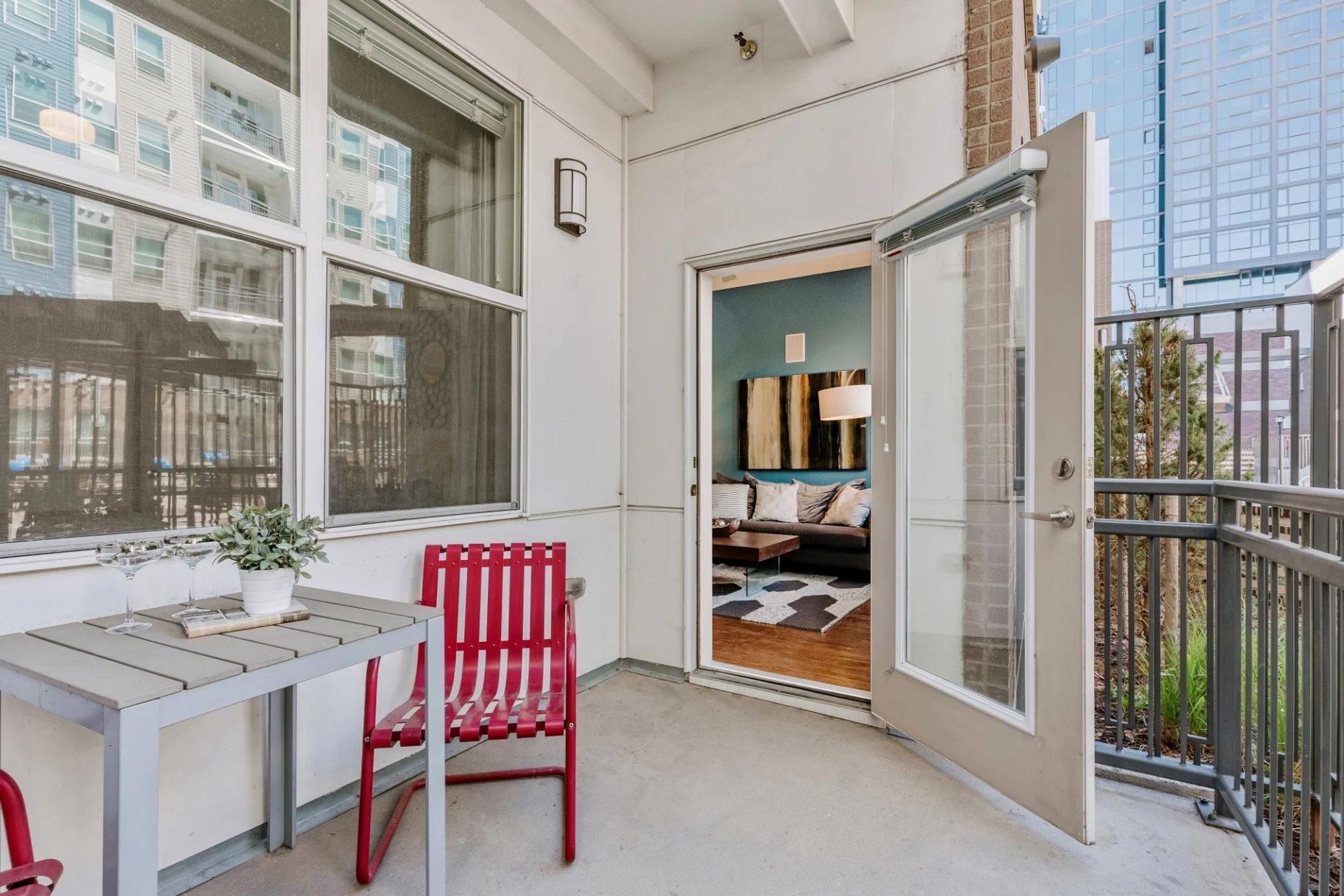 A balcony with a table and chairs and a sliding glass door leading to a living room.