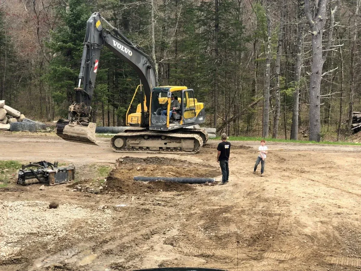 A volvo excavator is digging a hole in a dirt field.