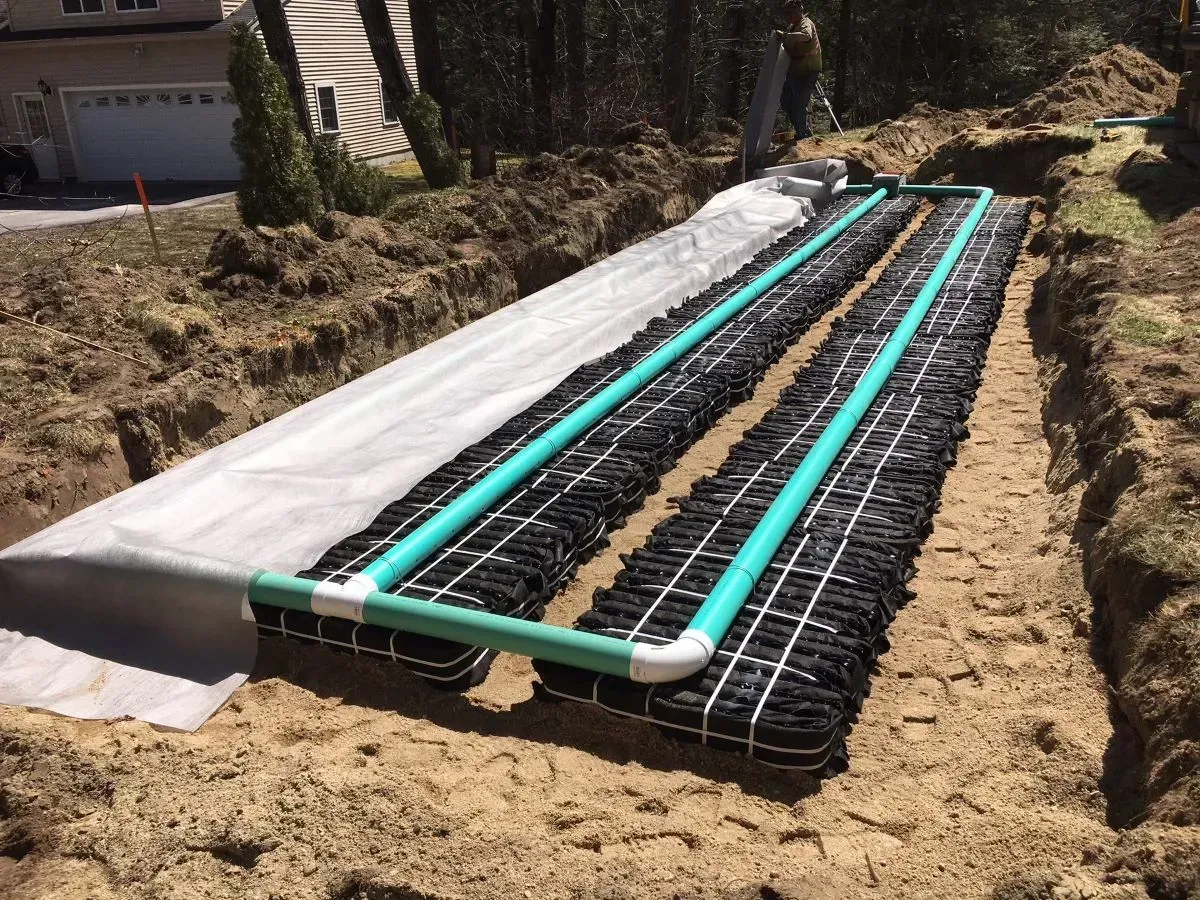 A septic system is being built in the dirt in front of a house.