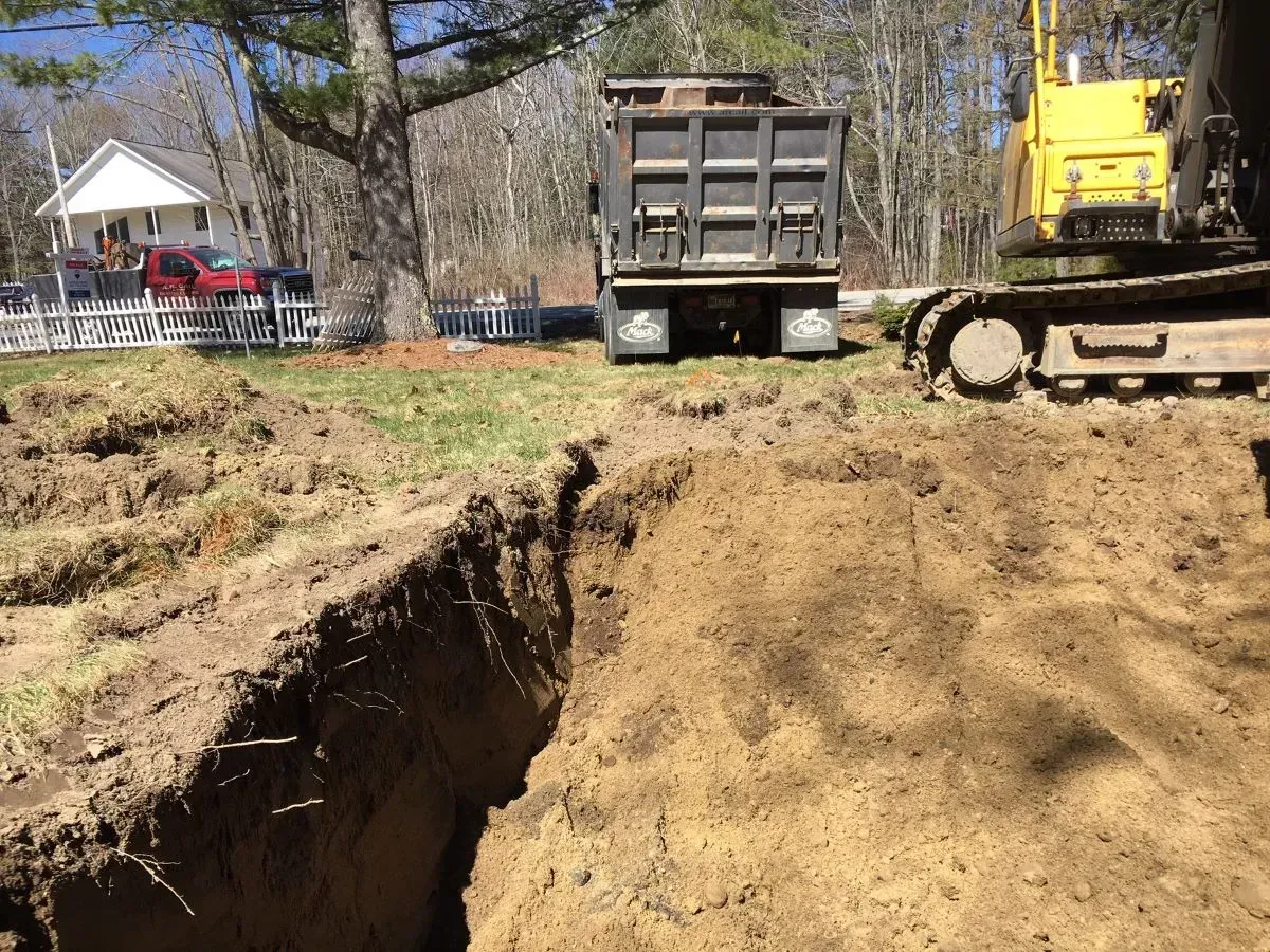 A dump truck is driving down a dirt road next to a bulldozer.