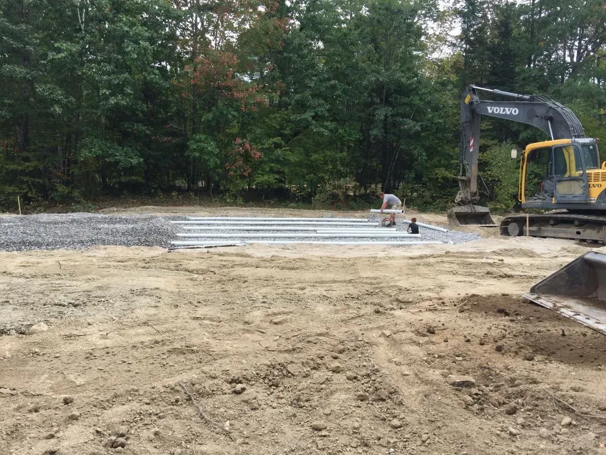 A yellow excavator is sitting in the middle of a dirt field.
