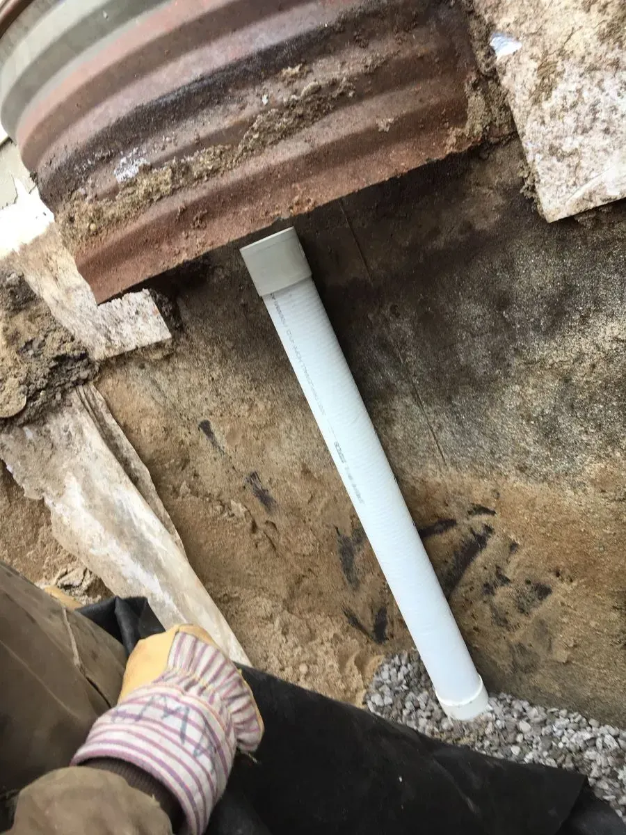 A person is working on a pipe in the ground.