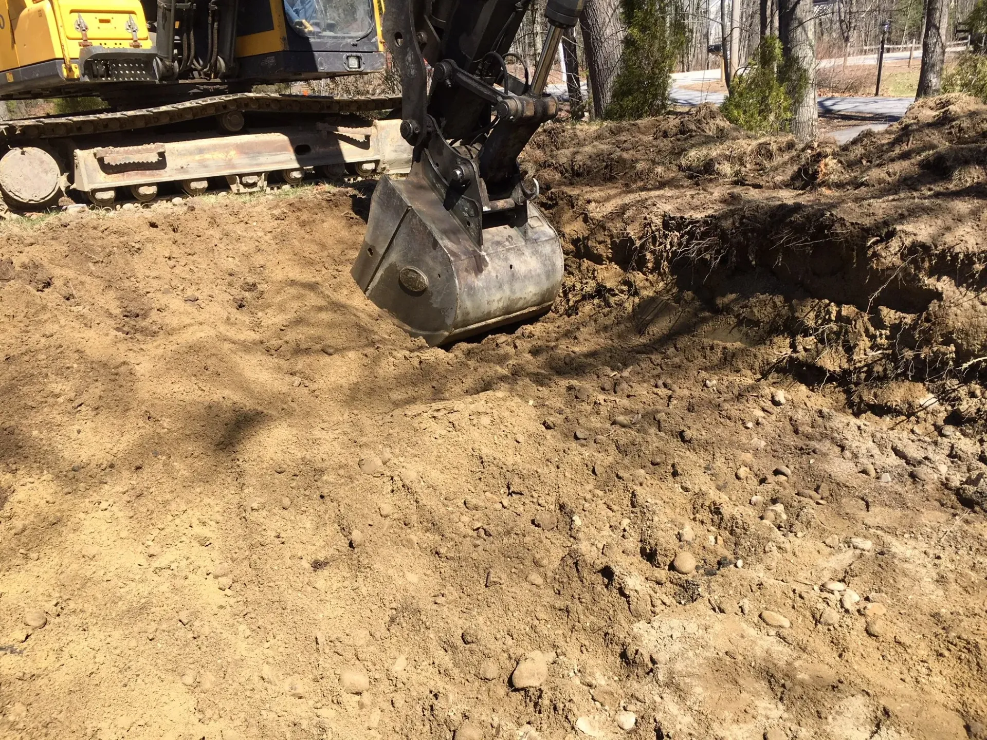 A yellow excavator is digging a hole in the dirt.