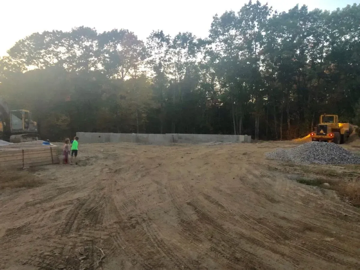 A construction site with a lot of dirt and trees in the background.