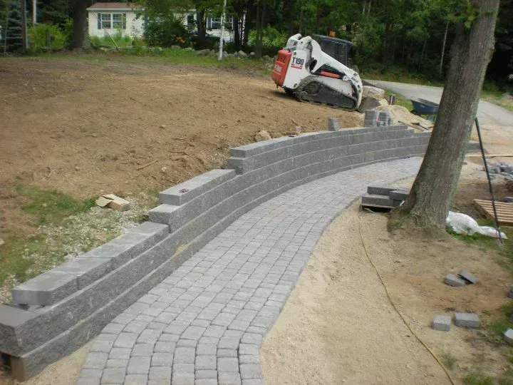 A bobcat is sitting next to a brick walkway being built.