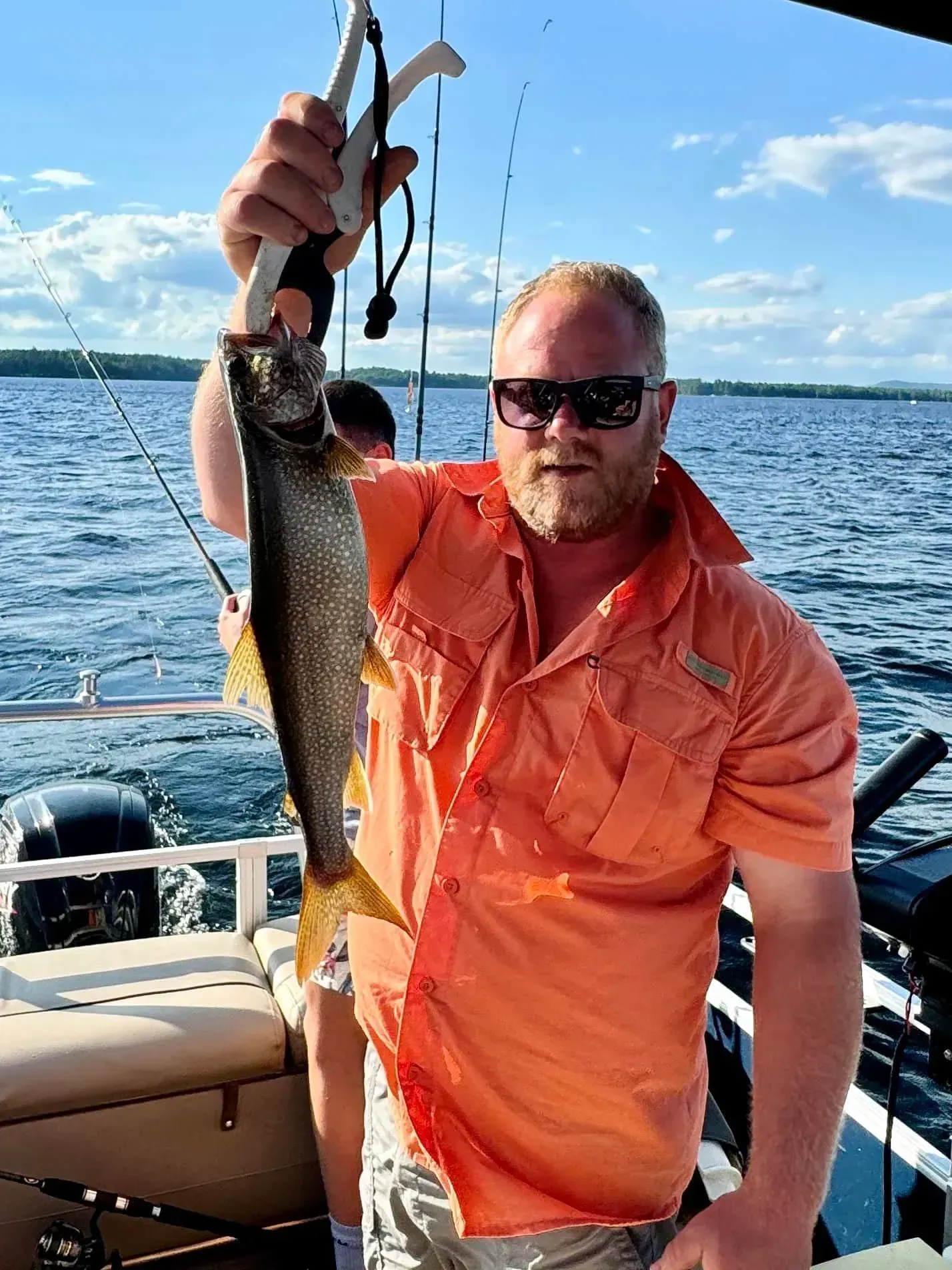 A man is holding a fish in his hand on a boat.