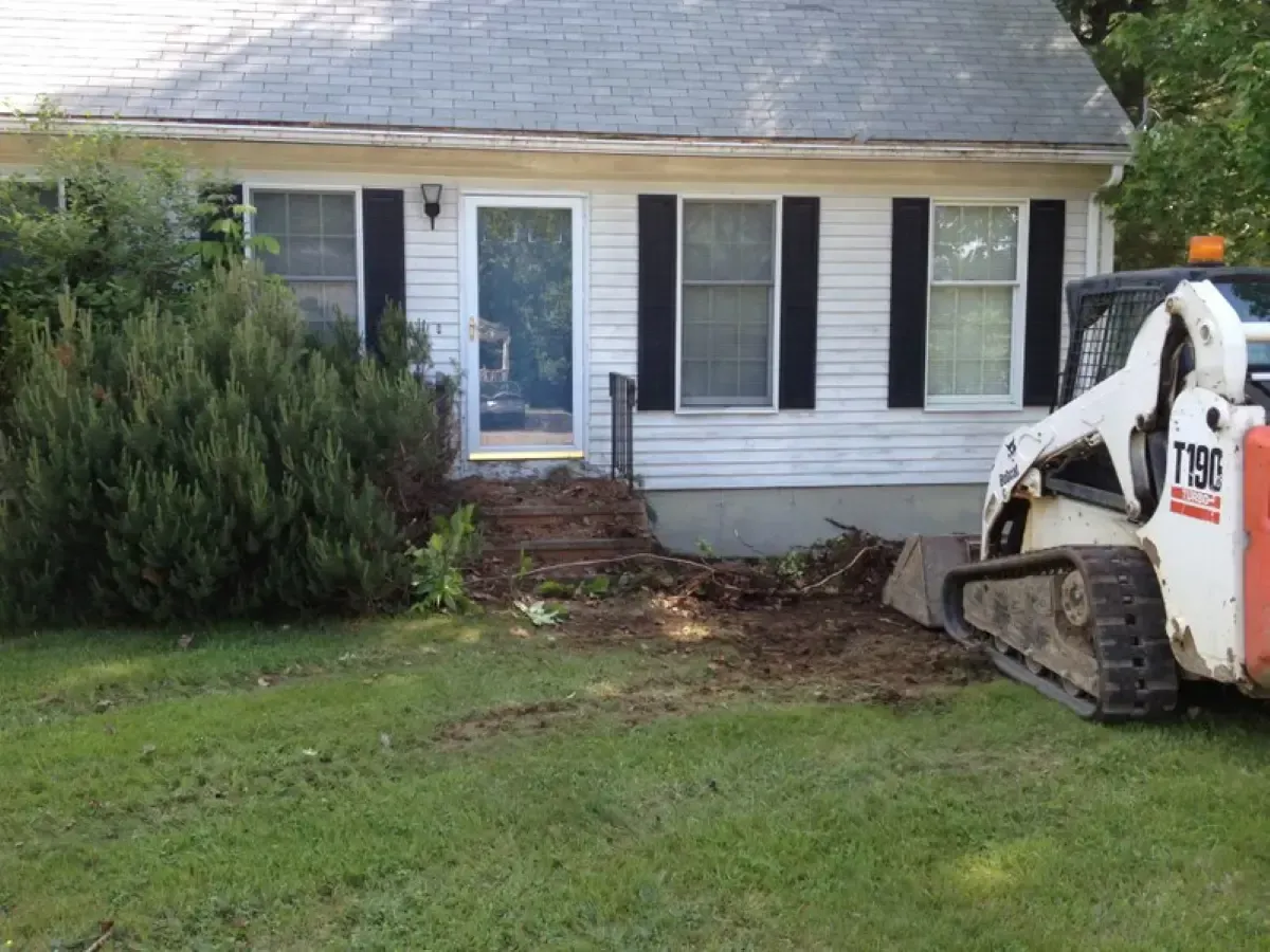 A bobcat is parked in front of a house.
