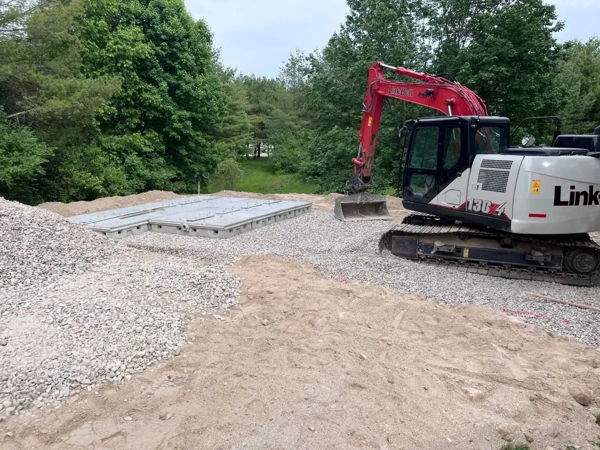 A white and red excavator is sitting on top of a pile of gravel.