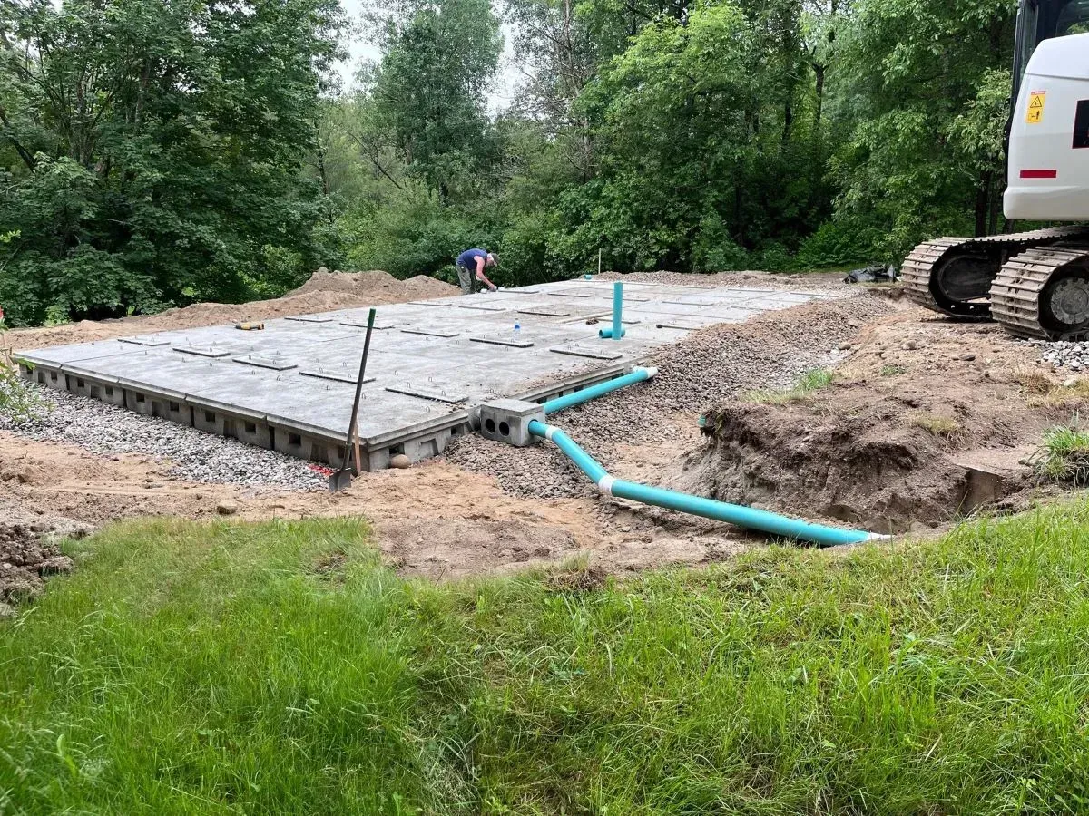 A construction site with a bulldozer and pipes in the dirt.