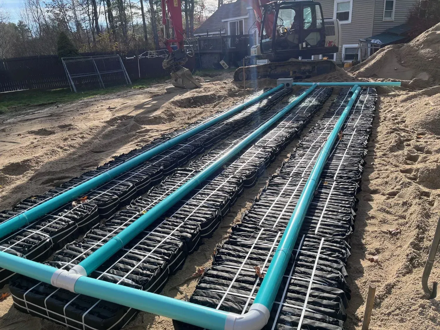 A septic system is being built in the dirt in front of a house.