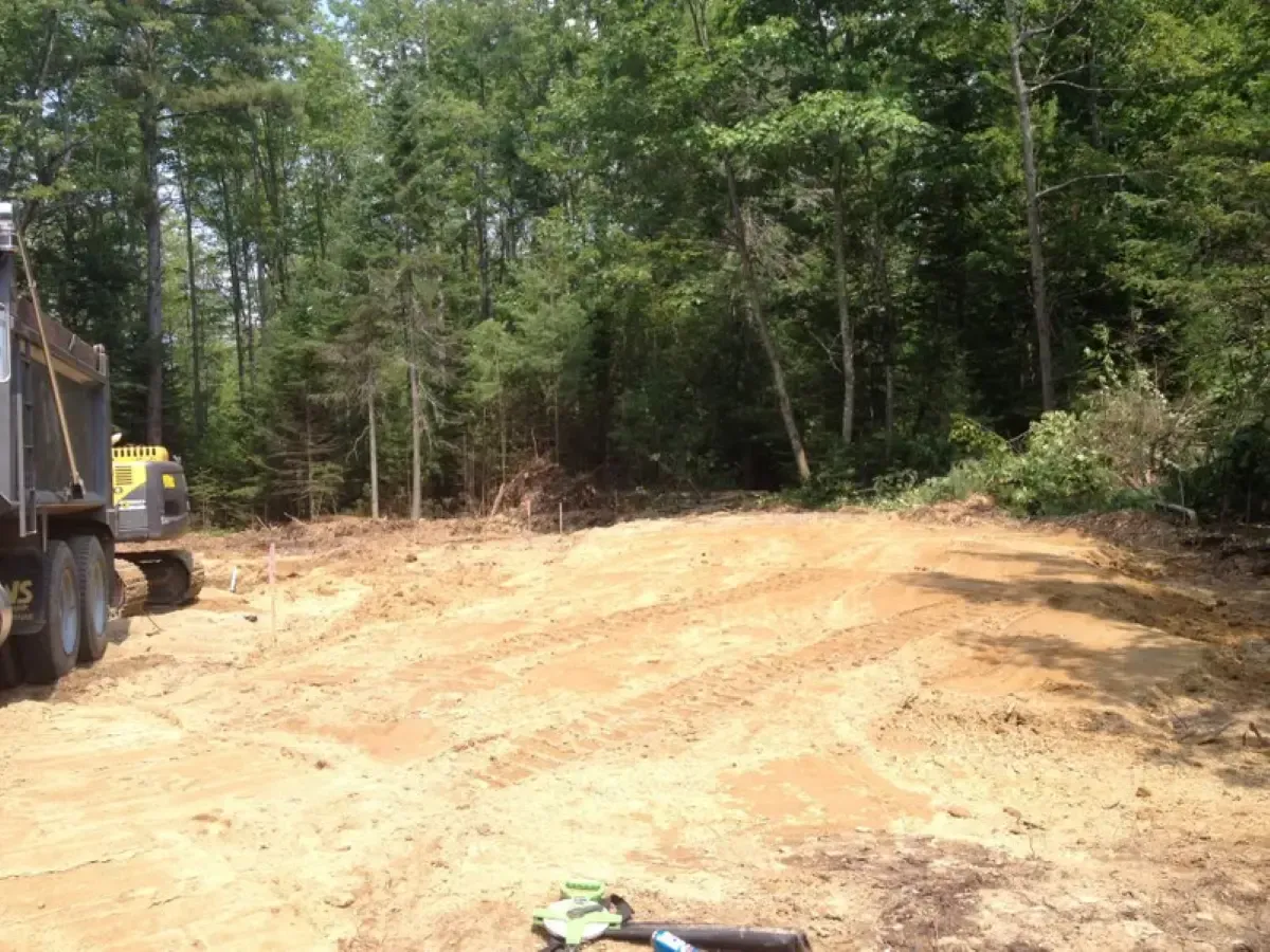 A dump truck is driving down a dirt road in the middle of a forest.