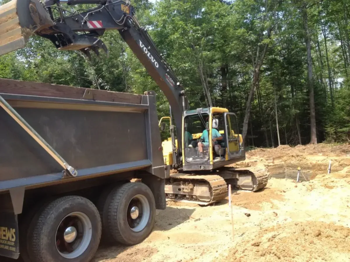 A volvo excavator is loading dirt into a dump truck