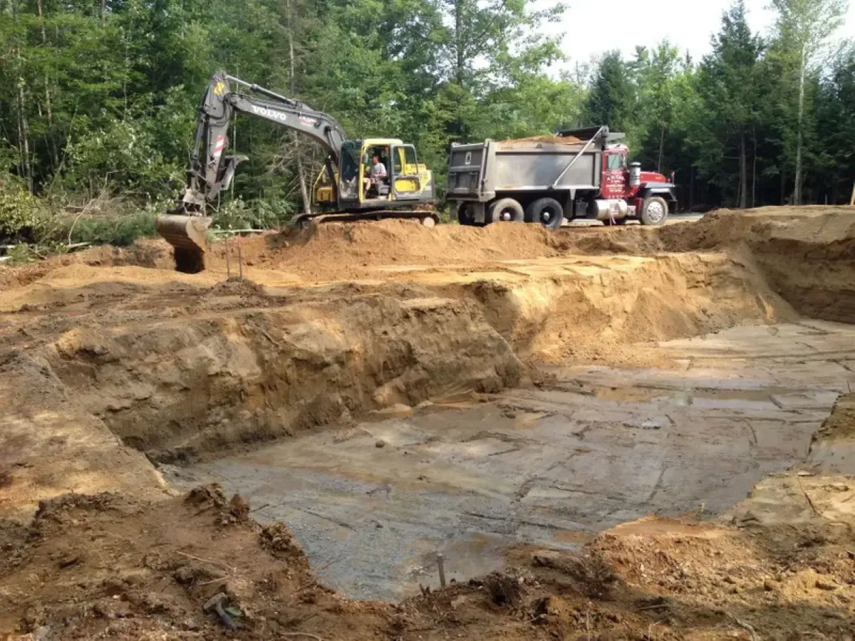 An excavator is digging a hole in the ground next to a dump truck.