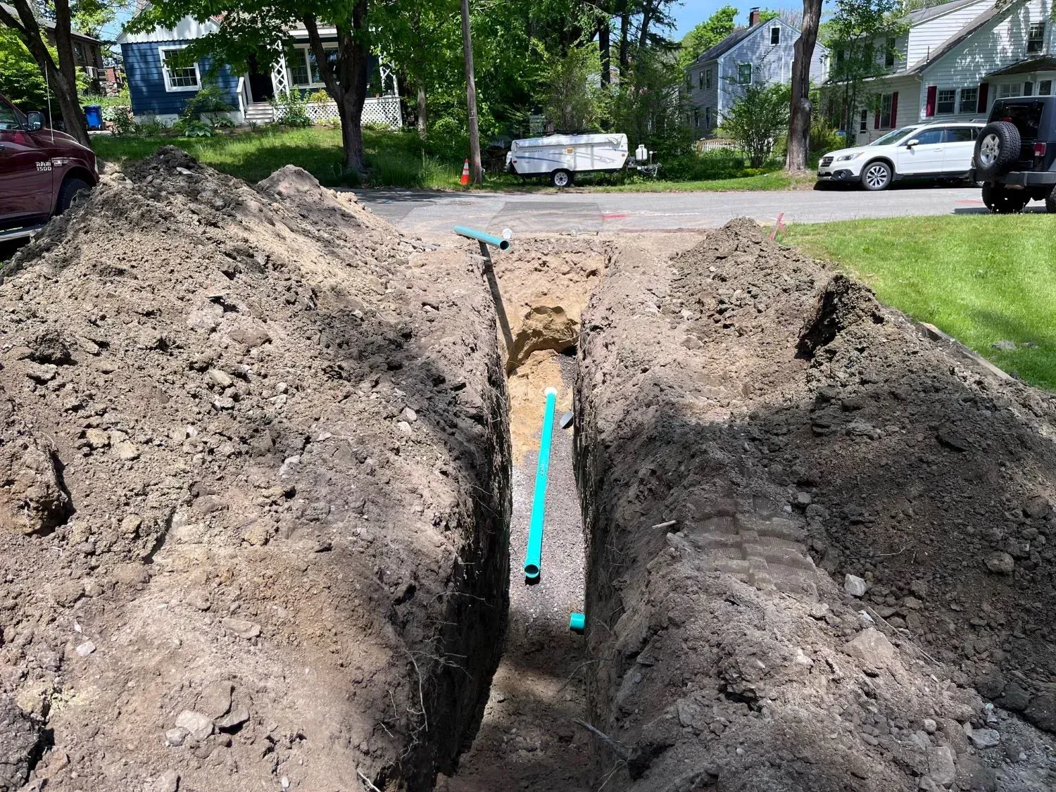 A blue pipe is being installed in a hole in the ground.
