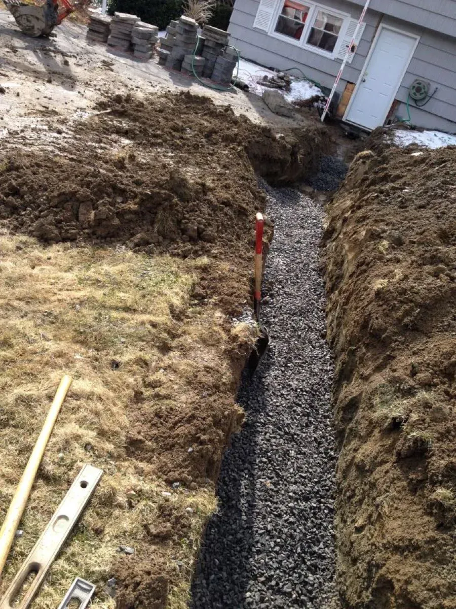 A shovel is sitting in the middle of a pile of dirt next to a house.