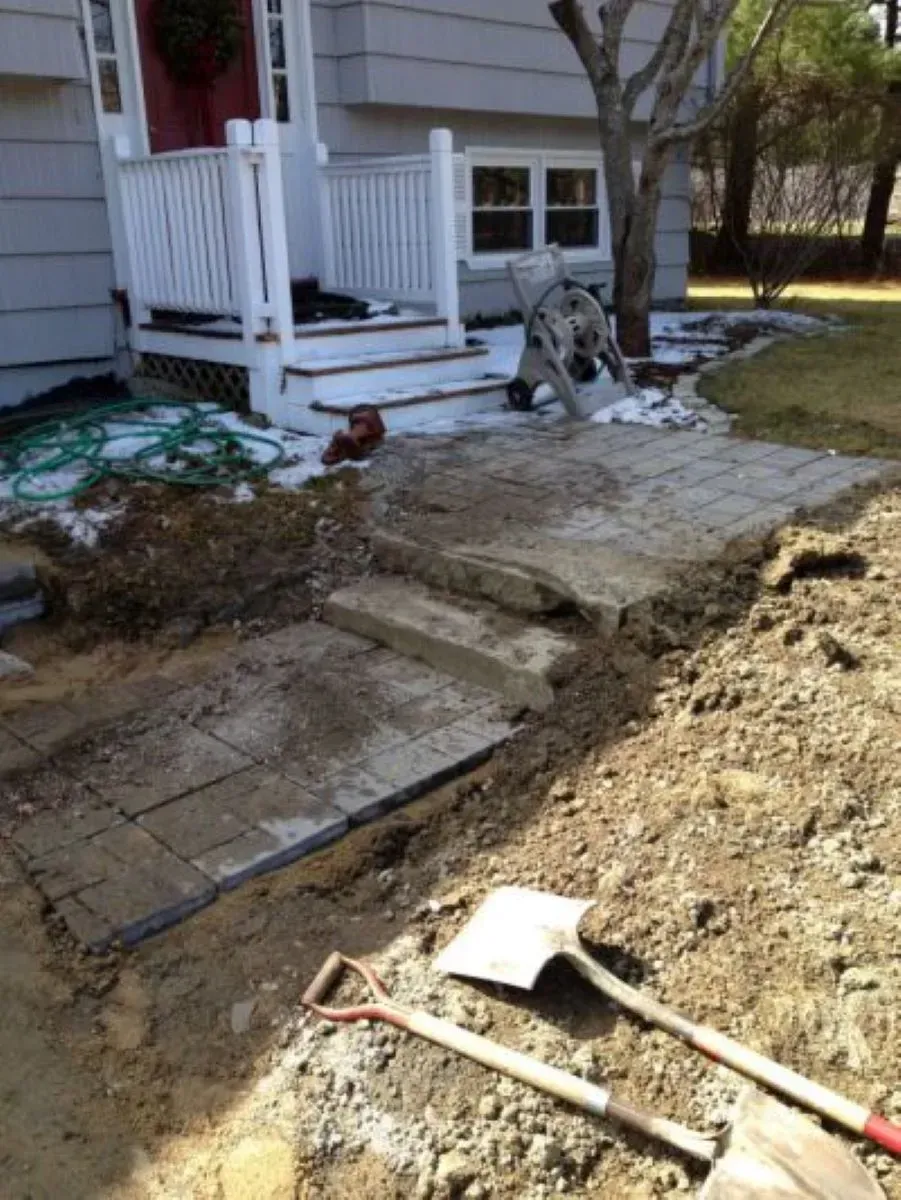 Two shovels are laying in the dirt in front of a house