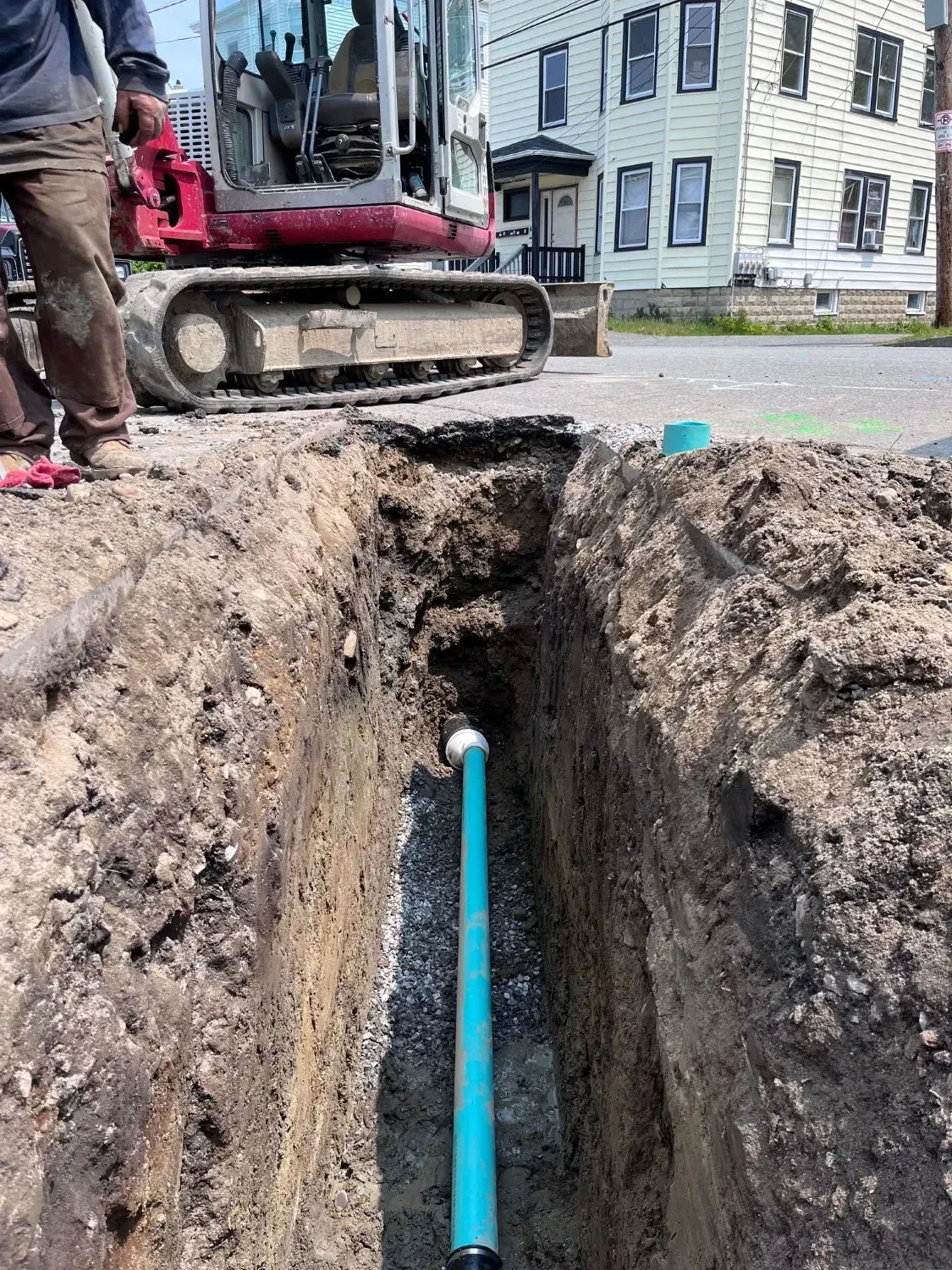 A blue pipe is being installed in a trench next to a bulldozer.