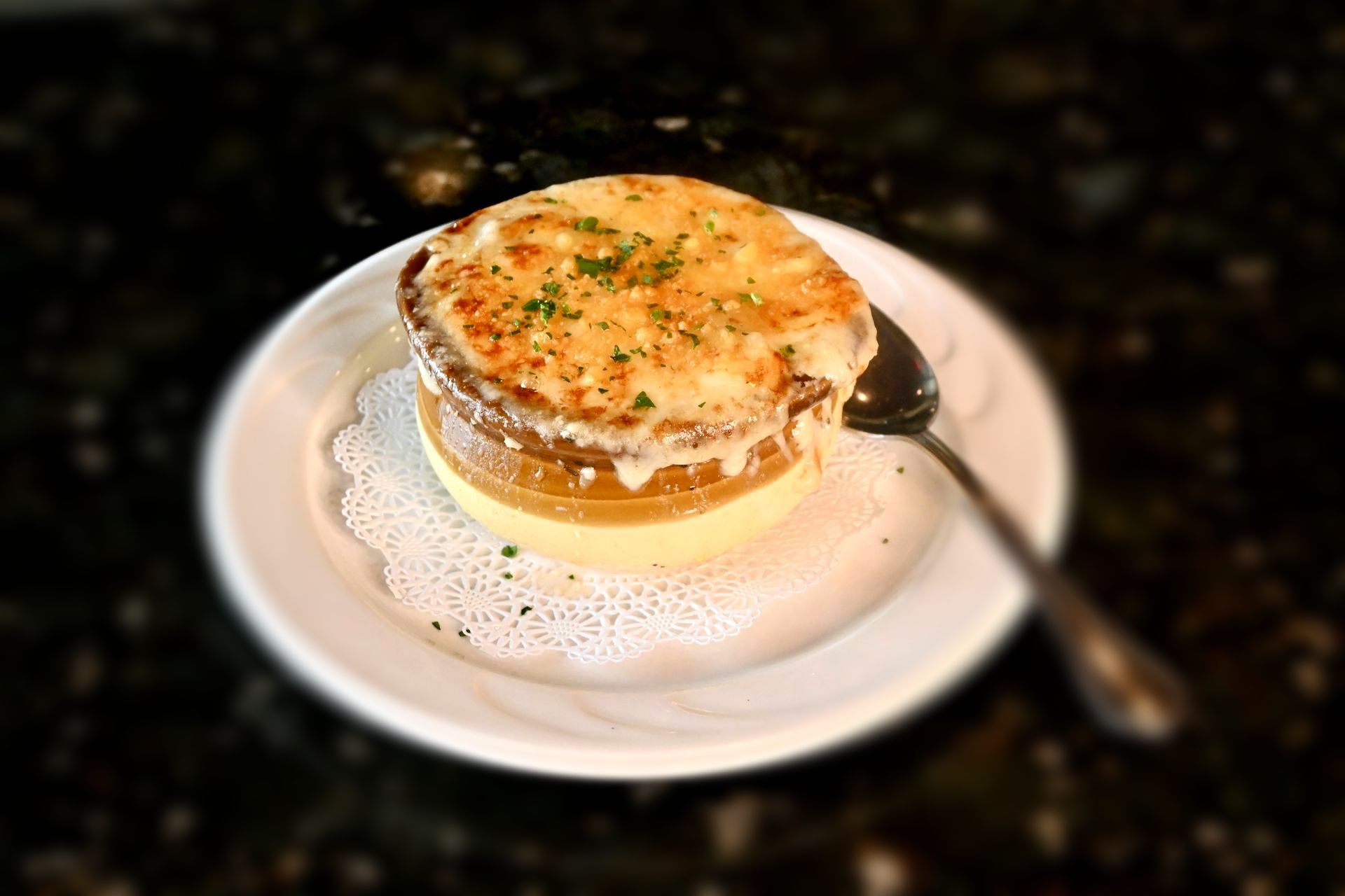Classic French onion soup au gratin topped with toasted bread and melted, bubbling Gruyère cheese in a rustic bowl