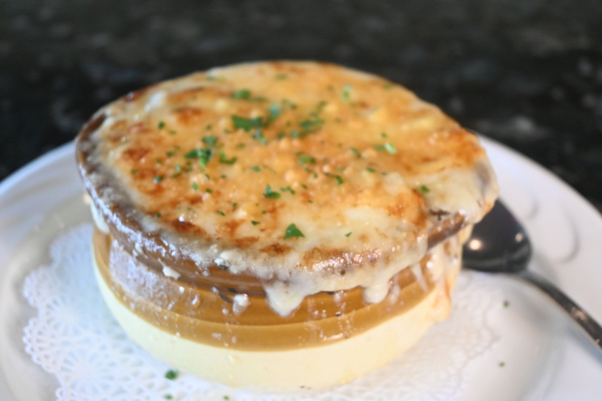 Traditional French onion soup crowned with melted Gruyère and toasted bread, served piping hot in a rustic crock.