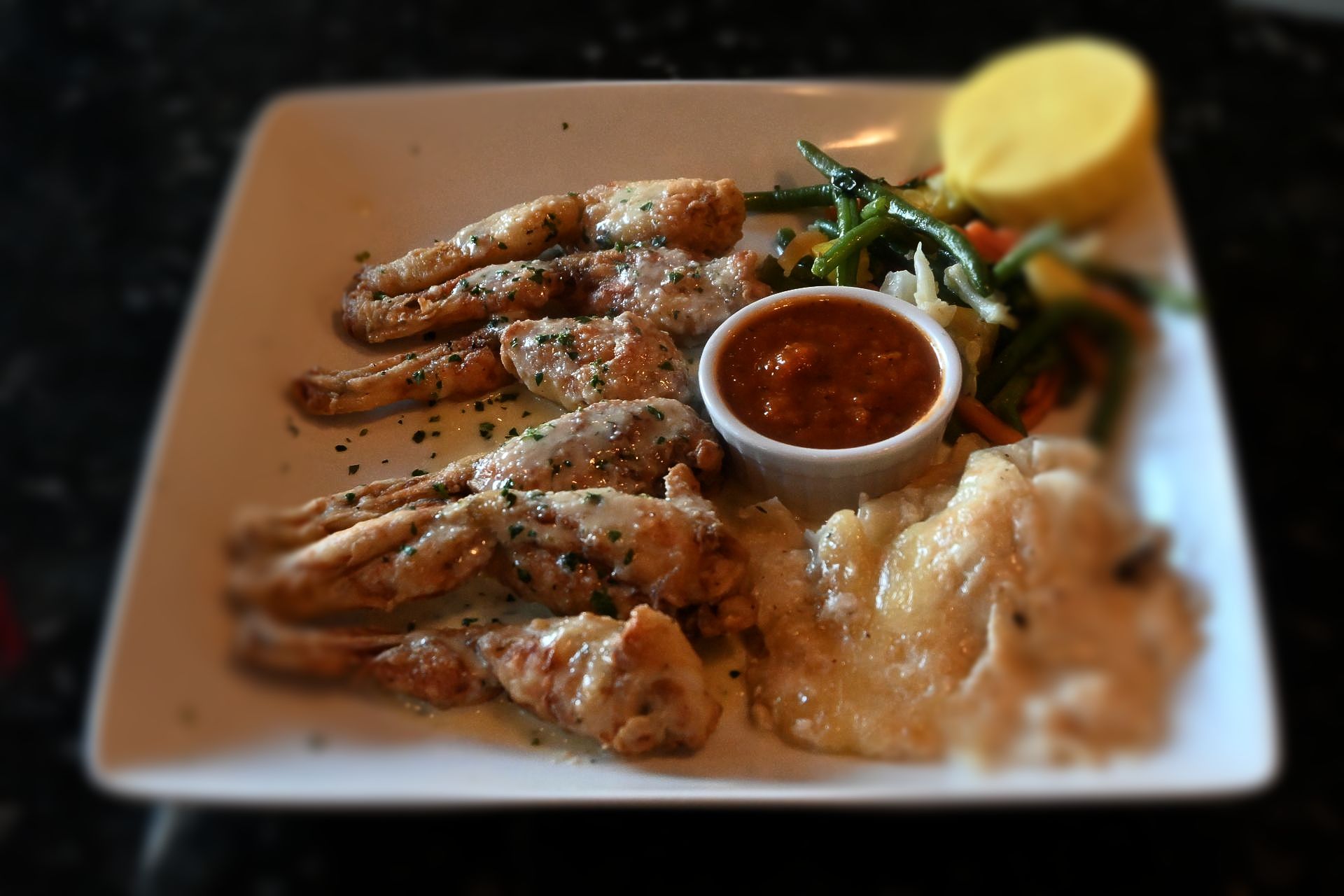 Frog Legs Sauté Provençale served with garlic, parsley, and herbs, presented in classic French bistro style.