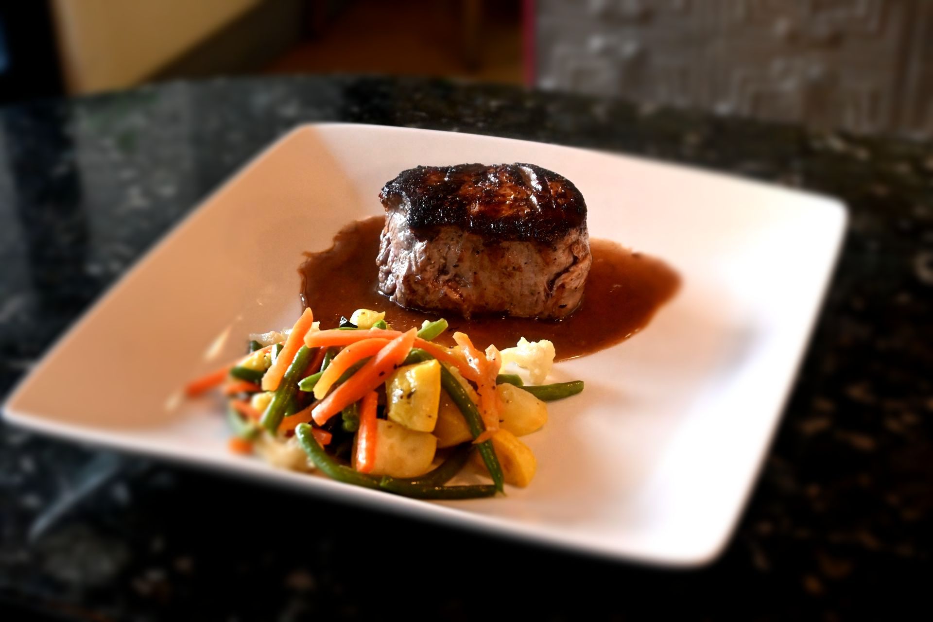 Steak Au Poivre featuring a seared filet with a peppercorn crust and creamy cognac peppercorn sauce, plated in elegant French bistro style