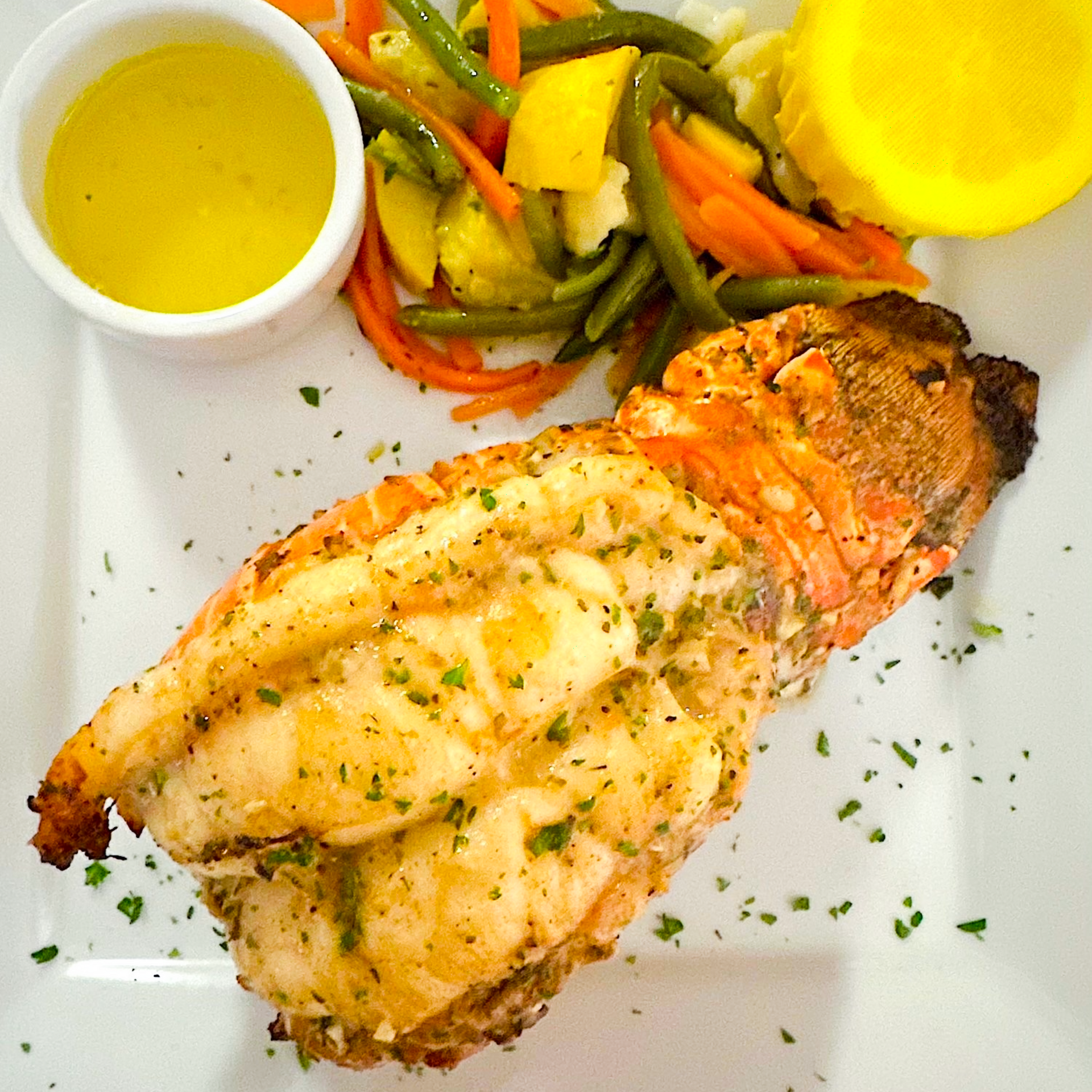 Lobster served with seasonal vegetables and lemon, presented with classic French bistro elegance.