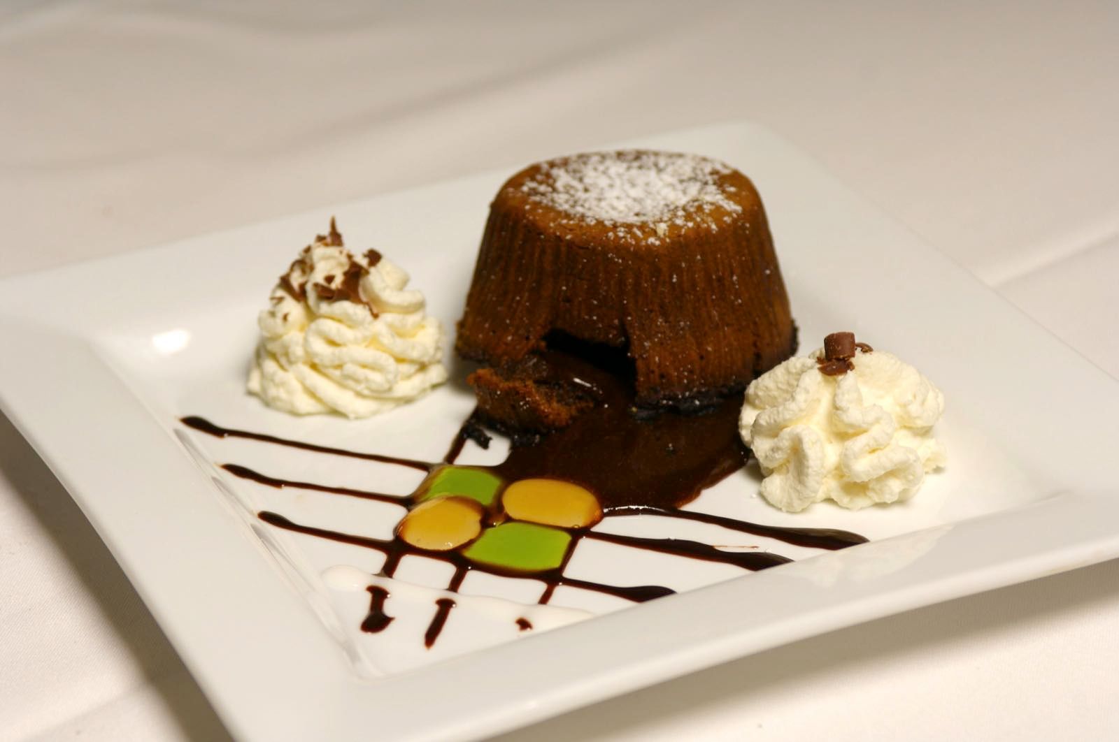 Molten chocolate lava cake with whipped cream and artistic chocolate drizzle, a signature Chez Pierre dessert.