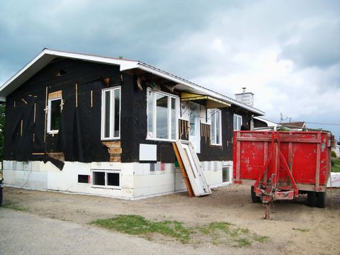 A red trailer is parked in front of a house under construction