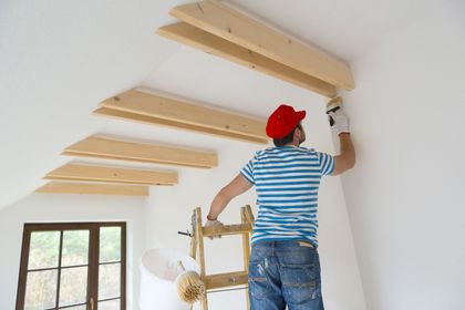 A man in a red hat is painting a wall