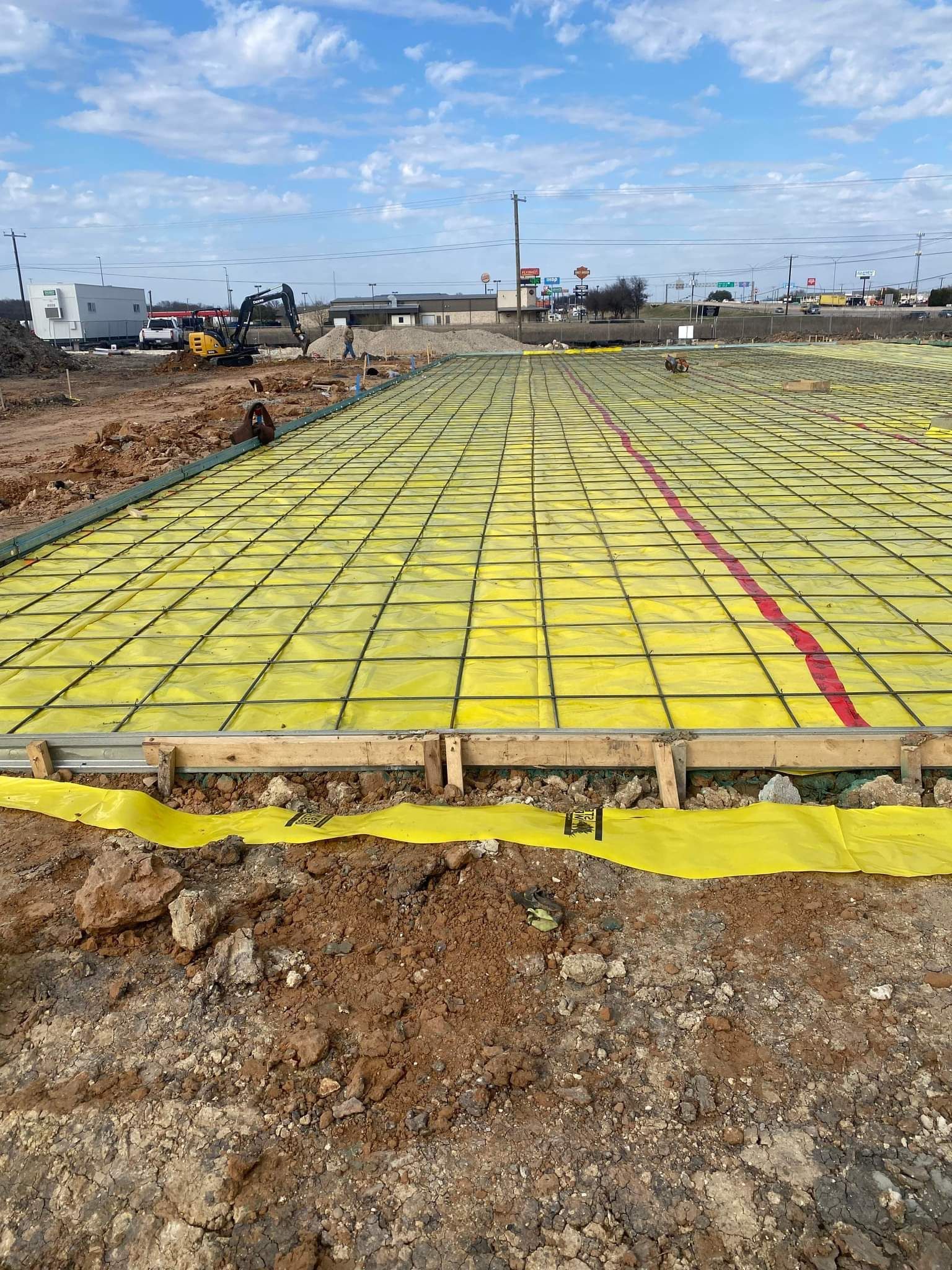 A concrete base is being built on a dirt field.