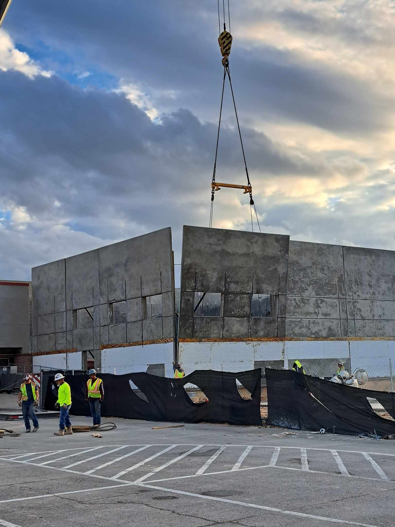 A crane is lifting a large piece of concrete in a parking lot.