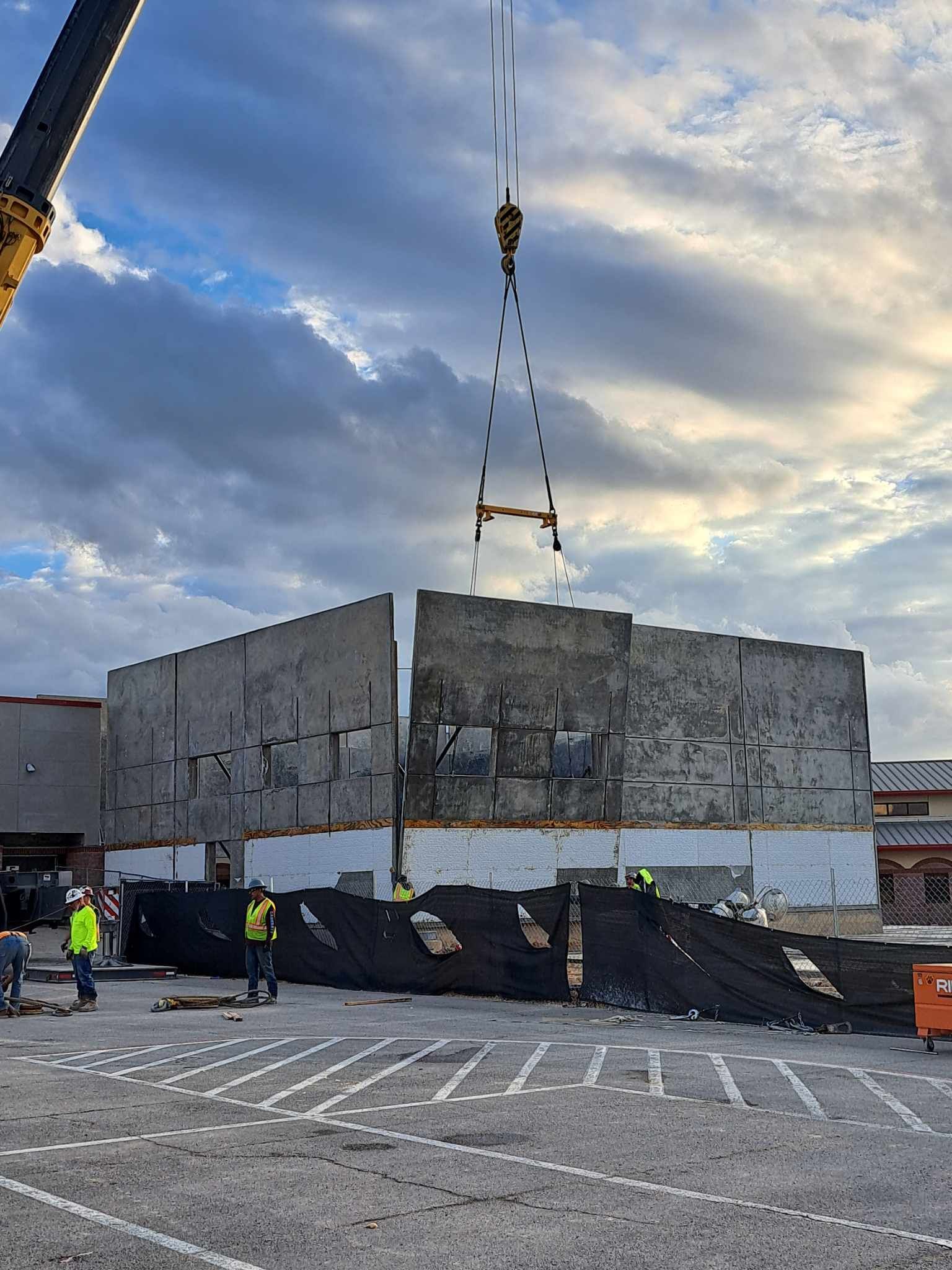 A large concrete wall is being lifted by a crane.