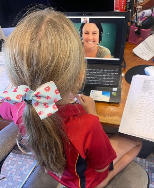 a little girl with a bow in her hair is sitting in front of a laptop computer
