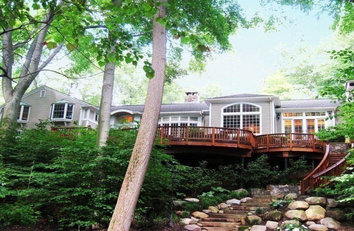 A large house with a large deck surrounded by trees