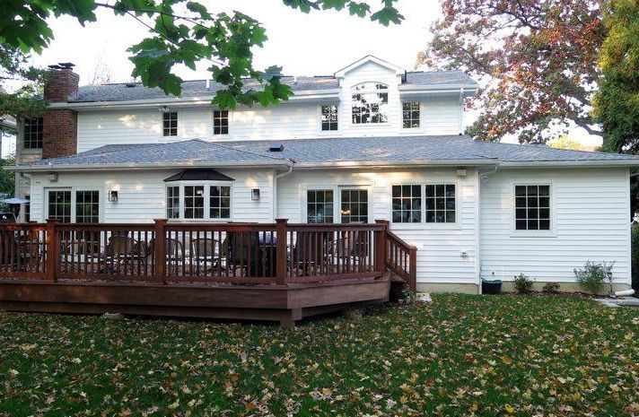 A large white house with a large deck in front of it
