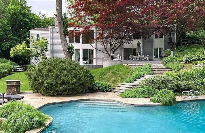 There is a large swimming pool in front of a house.