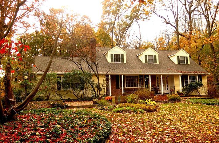 A house with a porch and a lot of leaves on the ground