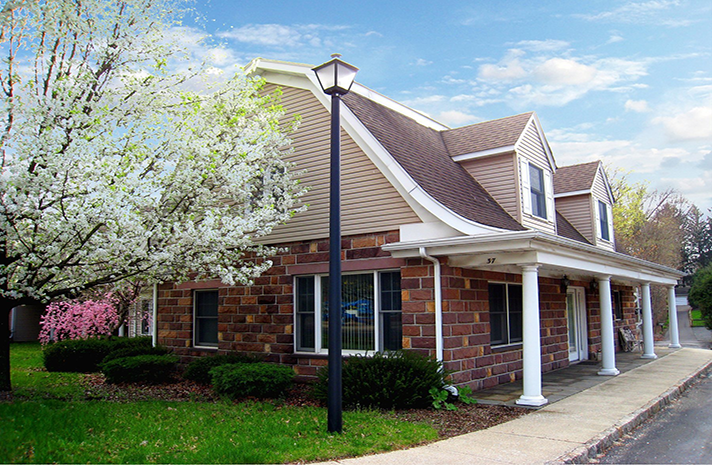 A large brick building with a porch and a lamp post in front of it.