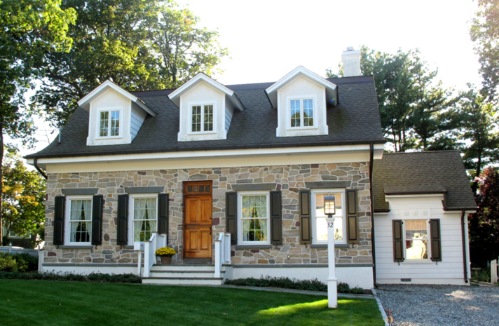 A stone house with white trim and black shutters