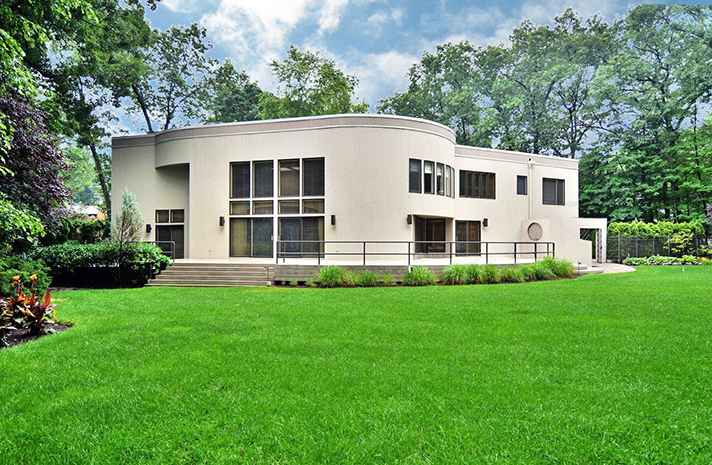 A large white house with a lush green lawn in front of it