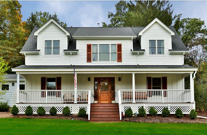 A white house with red shutters and a large porch