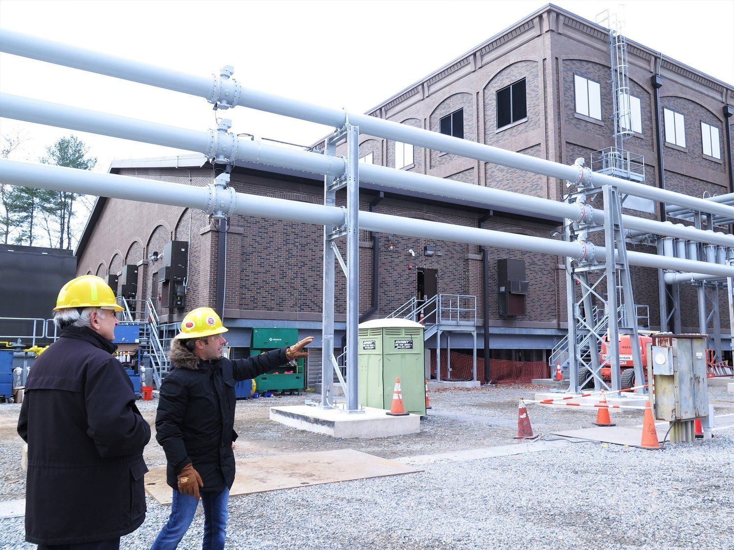 Two men wearing hard hats are standing in front of a building.