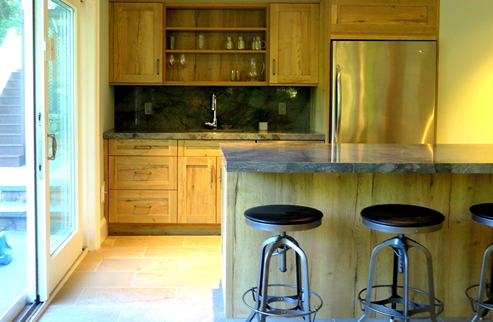 A kitchen with stools and a stainless steel refrigerator