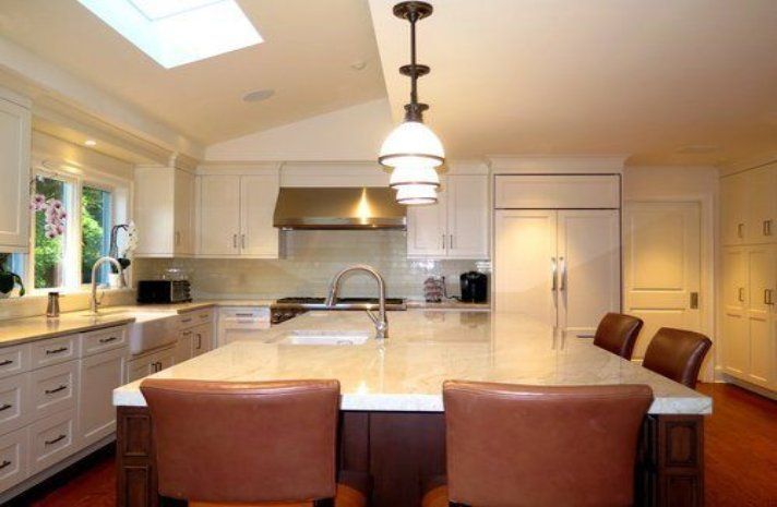 A kitchen with white cabinets and a large island