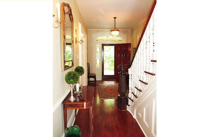 A hallway with stairs and a table in the middle