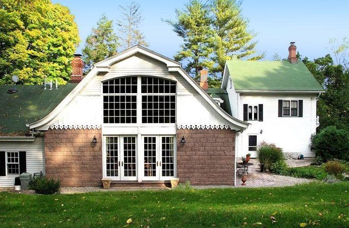 A white house with a green roof is next to a brick house