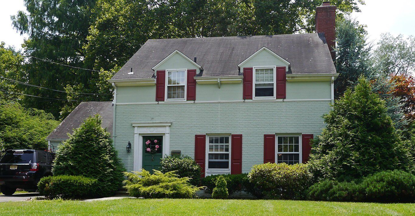 A green house with red shutters on the windows