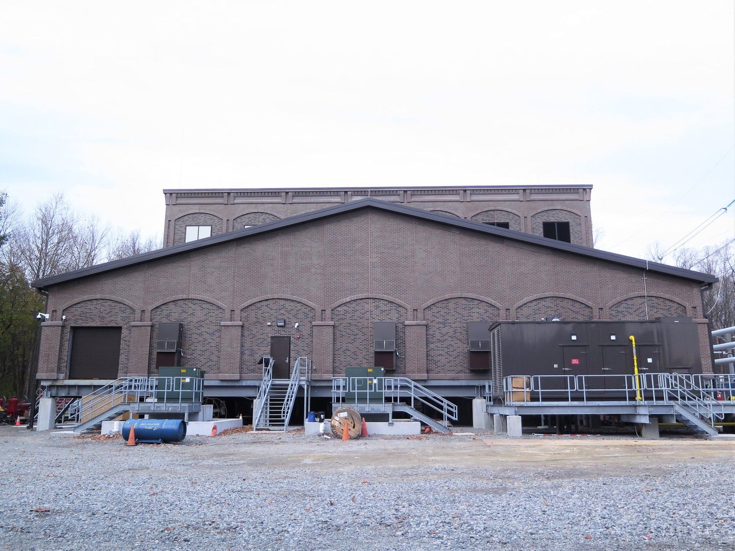 A large brick building is being built in a gravel lot.