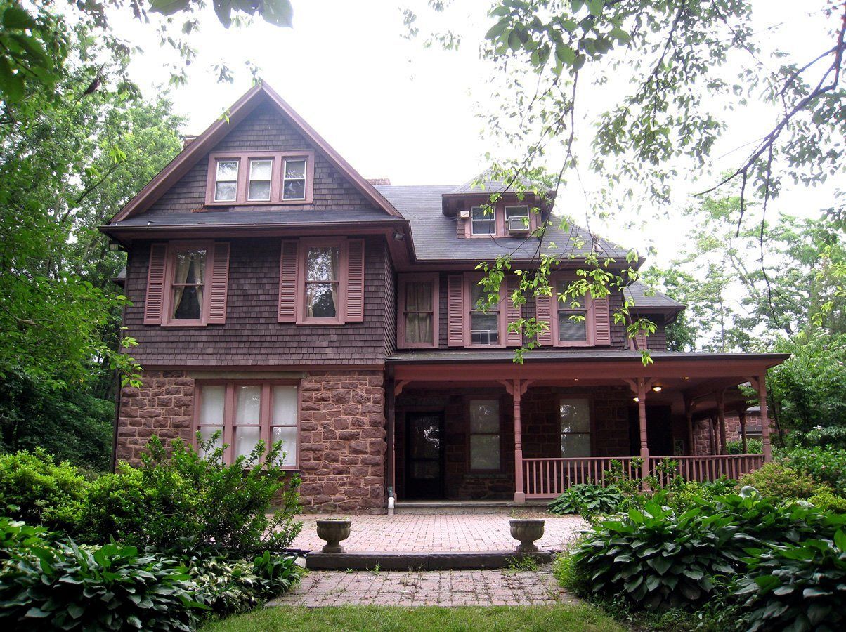 A large brick house with a porch surrounded by trees