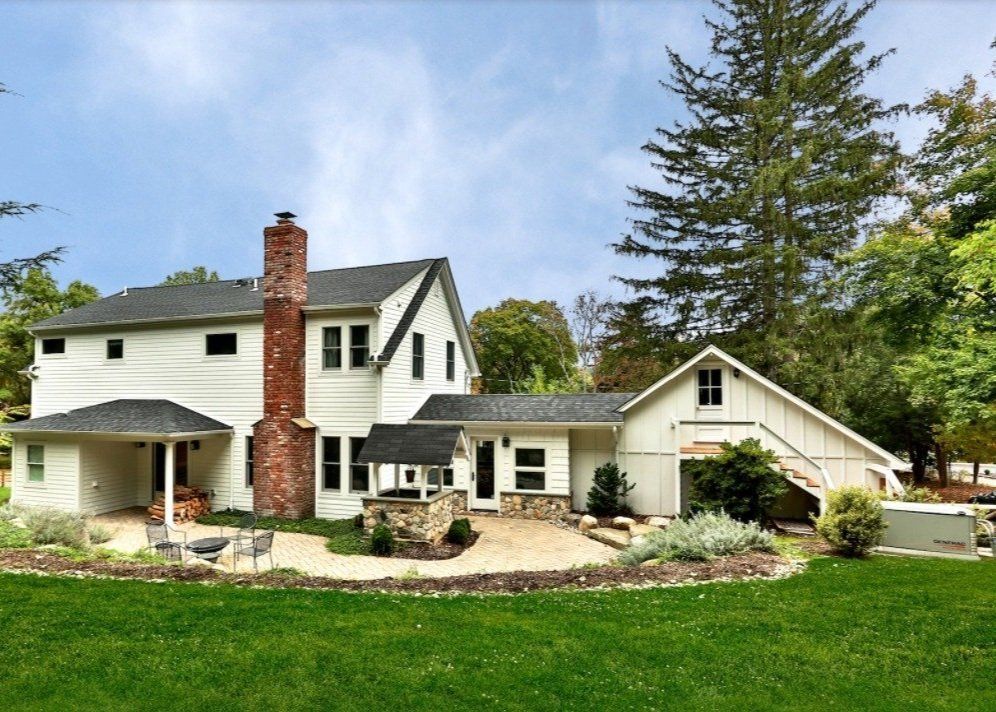 A large white house with a brick chimney in the backyard